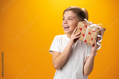 Portrait of a happy kid holding gift box over yellow background © fotofabrika