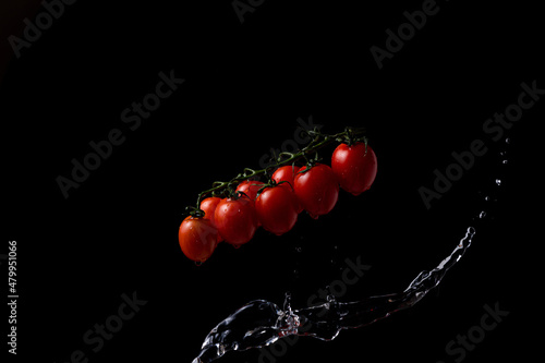 freeze motion. Cherry tomatoes on black background with splashing water