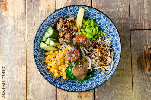 eel poke, edamame, cucumbers, corn, chukka, tomatoes and boiled rice top view on wooden table