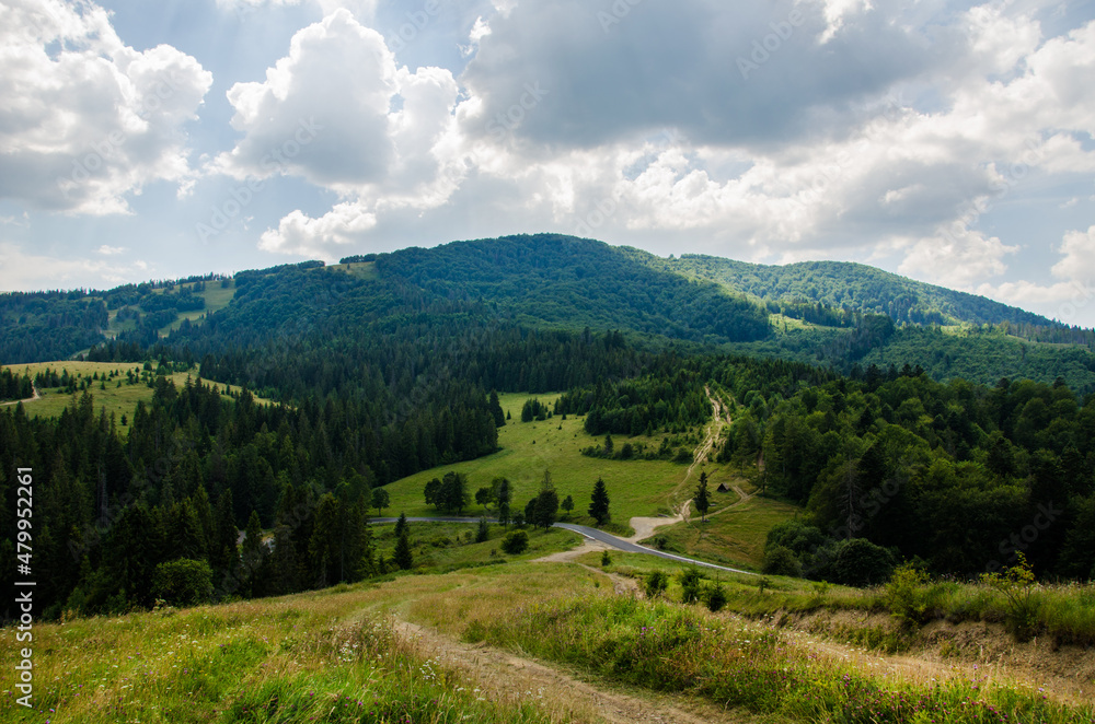 Hiking trail in the mountains highlands. Beautiful views of the mountains in the summer. Green trees and beautiful cloudy sky.