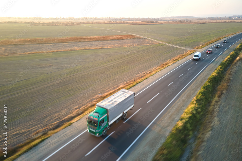 Aerial view of semi-truck with cargo trailer driving on highway hauling goods in evening. Delivery transportation and logistics concept Aerial view of semi-truck with cargo trailer driving on highway hauling goods in evening. Delivery transportation and logistics concept
