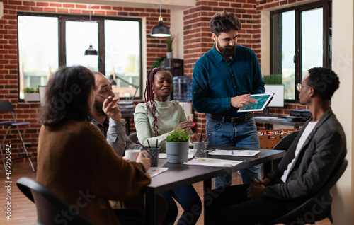 Entrepreneur man presenting company statistics during business meeting in startup office working at marketing strategy. Multiethnic businesspeople brainstorming ideas for management project