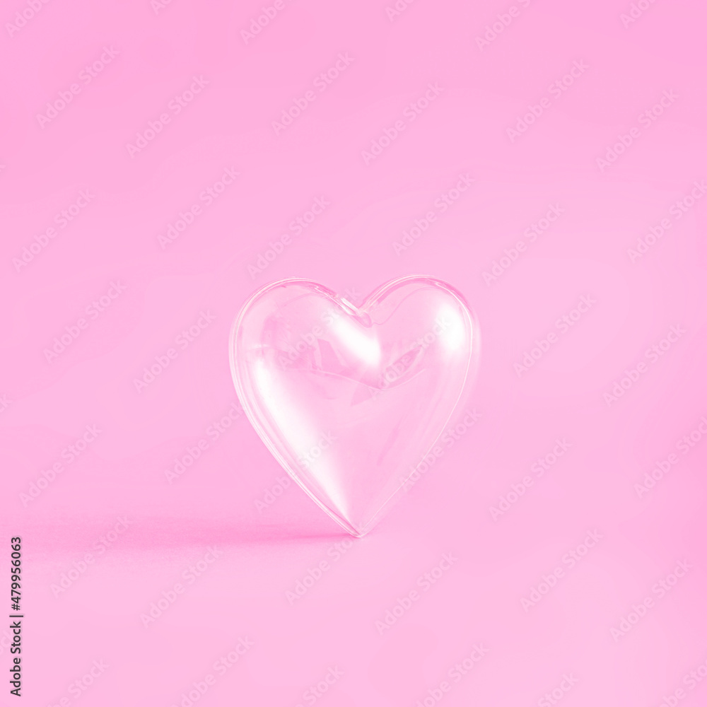 Creative love composition with transparent heart glass on colorful pink background. Minimal Valentine's or Women's day concept. Wedding, anniversary or romantic idea. Flat lay, copy space.