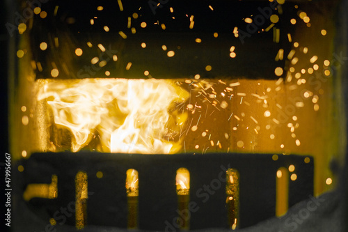 Fire and sparks in the furnace of a coal furnace, burning coal in the stove in cold winter, heating in winter