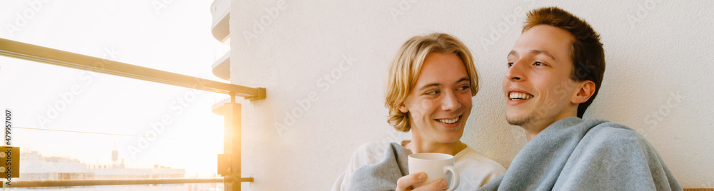European gay couple hugging while resting together on balcony