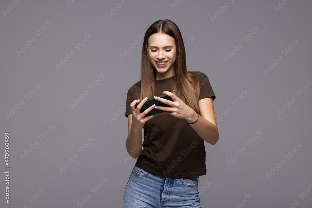 Young woman posing isolated over white wall background play games by mobile phone. Young woman posing isolated over white wall background play games by mobile phone.