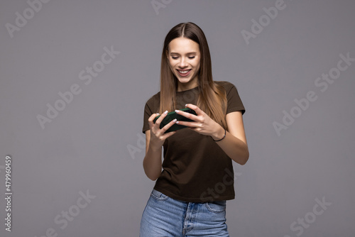 Young woman posing isolated over white wall background play games by mobile phone.