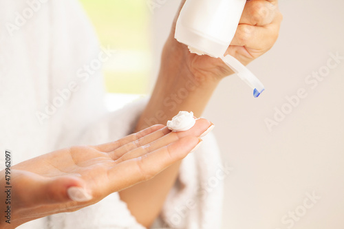 Closeup woman applying protective cream on hands.
