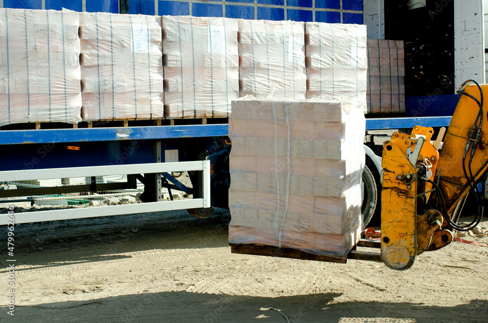 Naklejka premium HGV delivered concrete blocks on construction site and telehandler offloading it