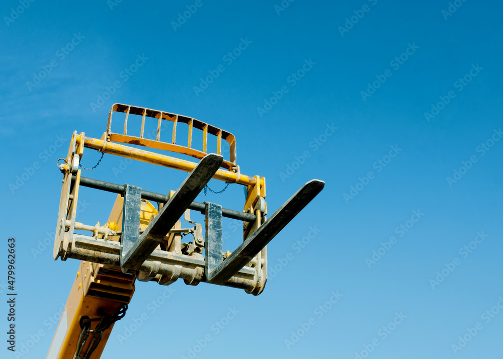 Telehandler with raised boom and forks on clear blue sky background Telehandler with raised boom and forks on clear blue sky background
