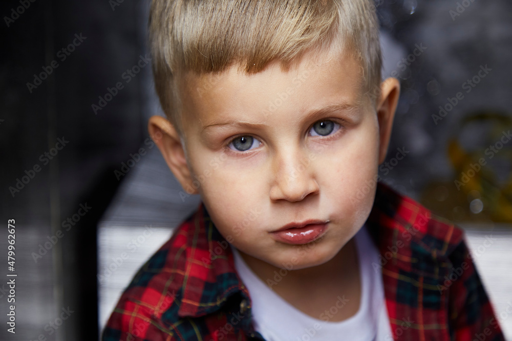 Portrait of handsome serious adorable kid close up. Atmospheric, aesthetic home for New Year's Eve. Silver cozy home, good mood Portrait of handsome serious adorable kid close up. Atmospheric, aesthetic home for New Year's Eve. Silver cozy home, good mood