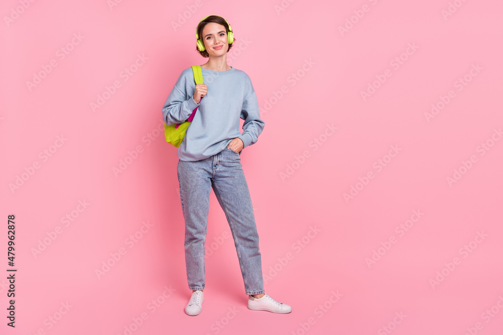 Full length photo of pretty young lady wear pullover jeans footwear headphones bag isolated on pink background Full length photo of pretty young lady wear pullover jeans footwear headphones bag isolated on pink background