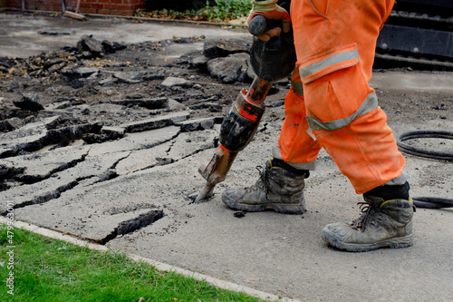 Canvas Print Construction worker breaking road gully using hydraulic breacker during road wor