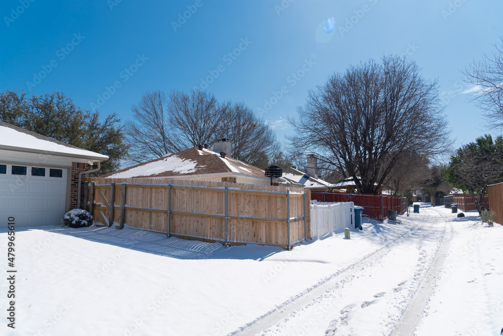 Snow covered the back alley of residential houses roofs and wooden fence after the historic blizzard near Dallas, Texas, USA