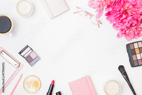 Fashion blogger workspace with notepad, glasses, cup of coffee, pencil and pink peonies on a white table. Flat lay banner or shop header with makeup cosmetic products