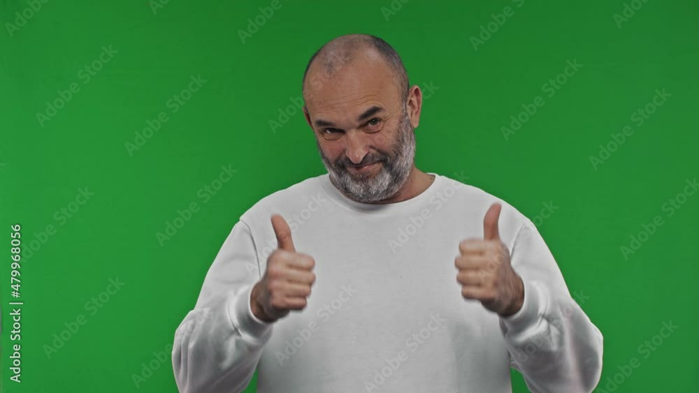 A man enthusiastically shows a thumb up with both hands. Portrait of a bearded man in a white hoodie. Green backgrond. Chroma key A man enthusiastically shows a thumb up with both hands. Portrait of a bearded man in a white hoodie. Green backgrond. Chroma key