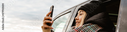 Asian woman taking selfie on mobile phone during car trip