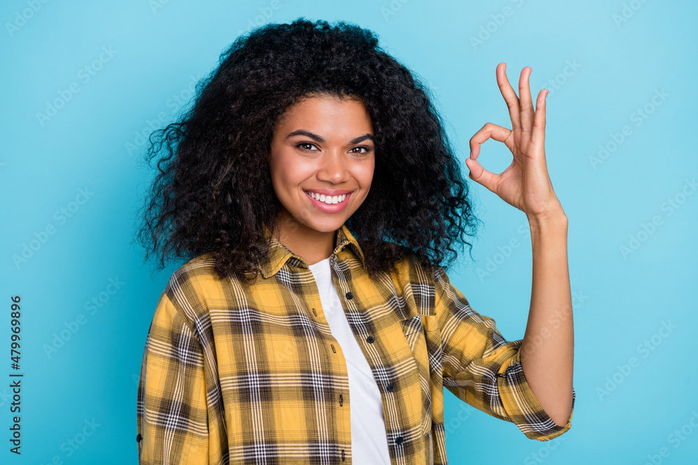 Photo of cheerful lady show okey symbol agree decision deal wear checkered shirt isolated blue color background Photo of cheerful lady show okey symbol agree decision deal wear checkered shirt isolated blue color background