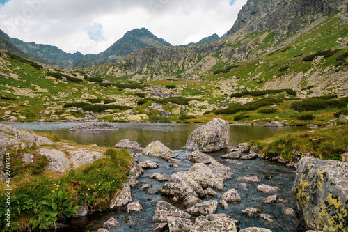 Beautiful lake in High Tatra mountains with stones in the middle and clouds reflections on water