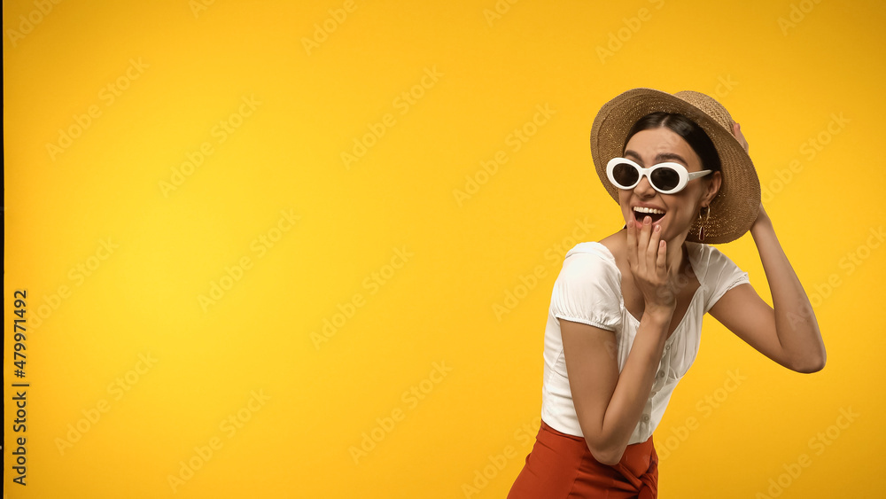 Excited brunette woman in straw hat and sunglasses isolated on yellow. Excited brunette woman in straw hat and sunglasses isolated on yellow.