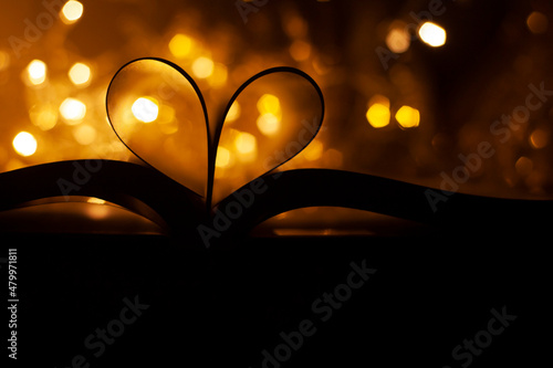 Heart shaped book pages on shiny bokeh background