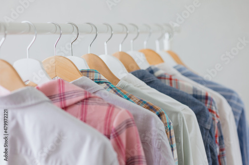 dressing room or rail with clothes on hangers shirts and dresses. a clothing store or boutique. a female stylist picks up a wardrobe or collects things for recycling. eco-friendly life and clothing
