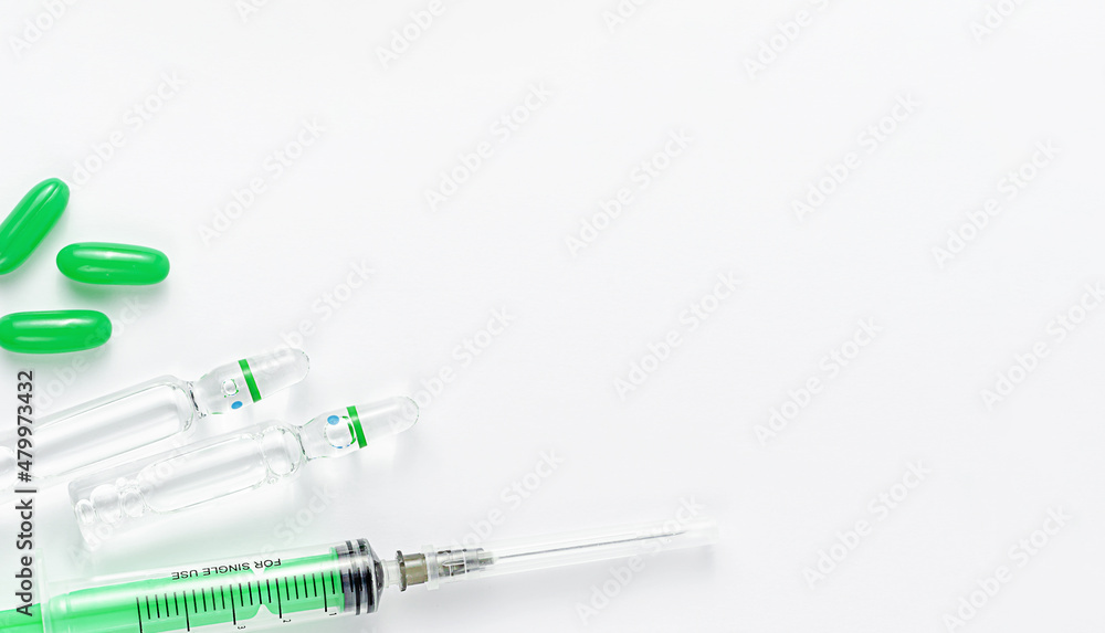 Syringe, ampules and green pills on white background. Medical treatment and vaccination concept. Copy space, overhead Syringe, ampules and green pills on white background. Medical treatment and vaccination concept. Copy space, overhead