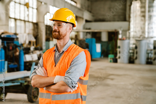 White man wearing helmet and vest working at factory