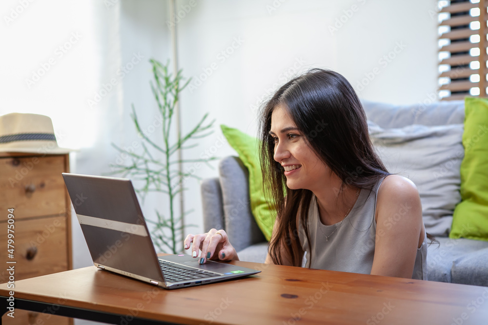 Beautiful young woman working on laptop computer while sitting at the living room Beautiful young woman working on laptop computer while sitting at the living room