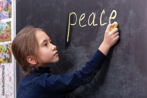 The girl writes the word peace on the blackboard..