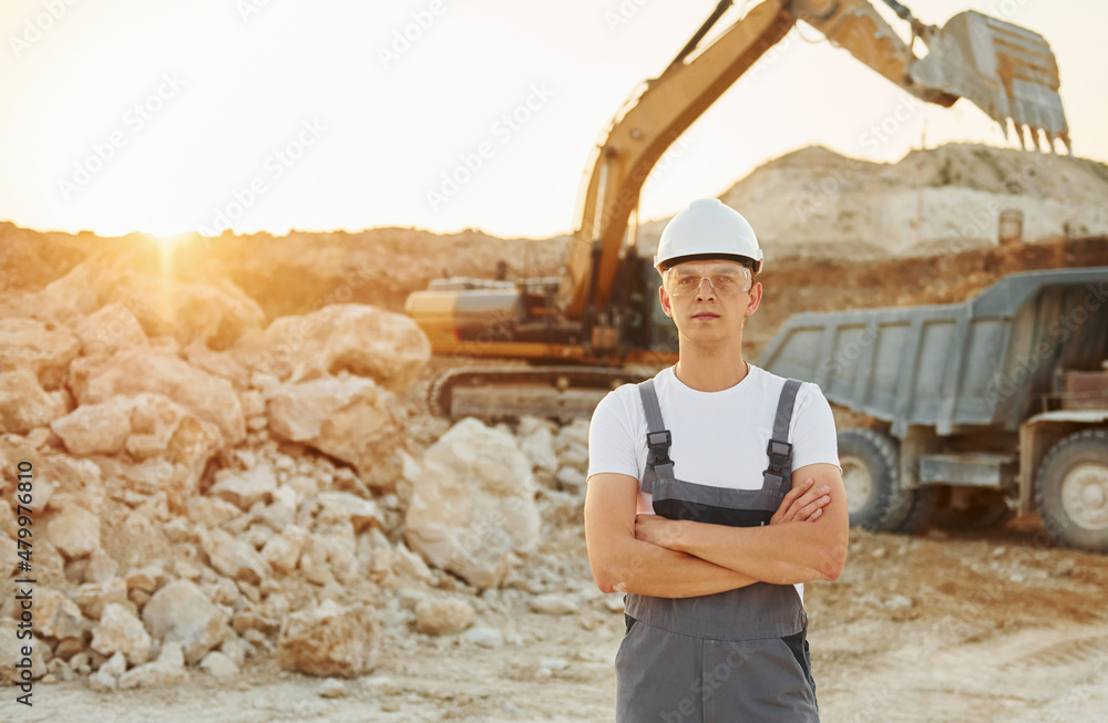Fototapeta premium Standing with arms crossed. Worker in professional uniform is on the borrow pit at daytime
