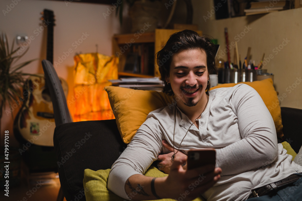 Fototapeta premium young man relaxing at home while using smartphone