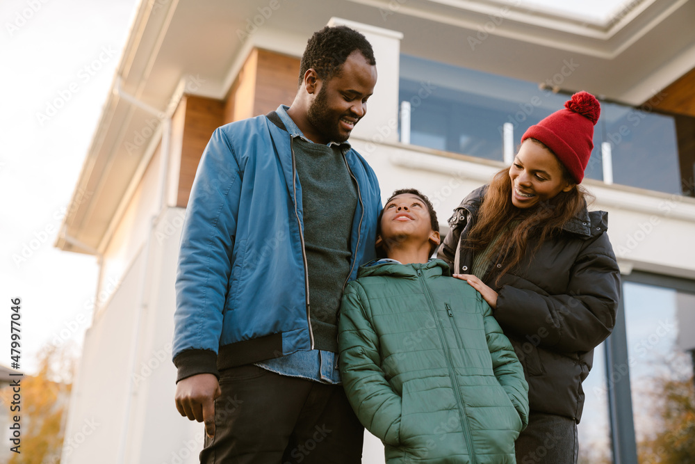 Fototapeta premium Black family smiling and talking while standing by house