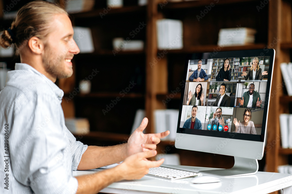 Successful caucasian young man talking on video conference with colleagues of different nationalities, discussing the project and strategy. Online business meeting, brainstorm of employees Successful caucasian young man talking on video conference with colleagues of different nationalities, discussing the project and strategy. Online business meeting, brainstorm of employees