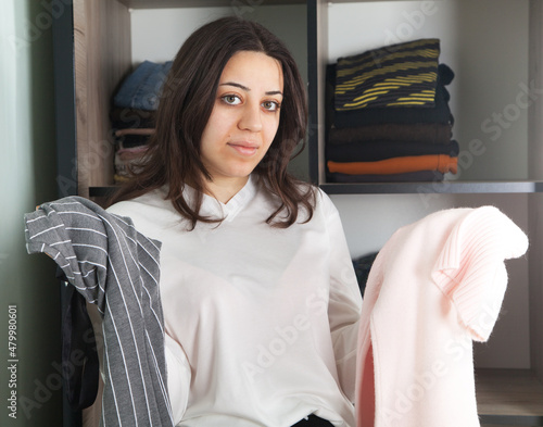 Beautiful woman chooses clothes from her wardrobe.