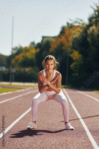 Photo in motion. Young woman in sportive clothes is exercising outdoors