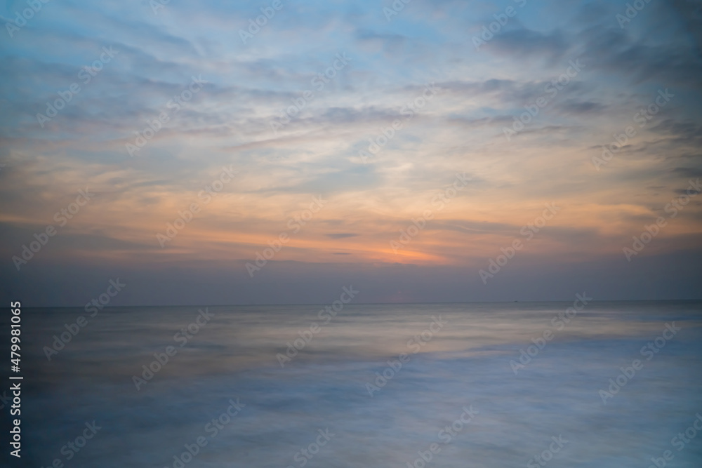 Beautiful long exposure of an amazing sunset from smooth wavy sea and cloud. orange horizon with sunrise sky.