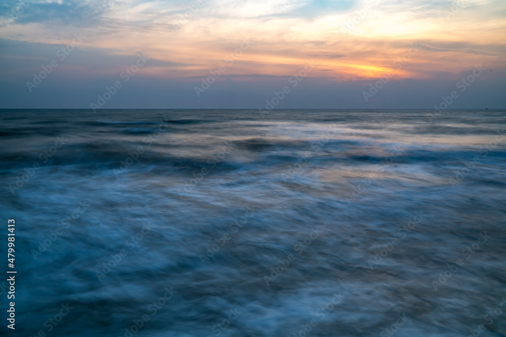 Beautiful long exposure of an amazing sunset from smooth wavy sea and cloud. orange horizon with sunrise sky.