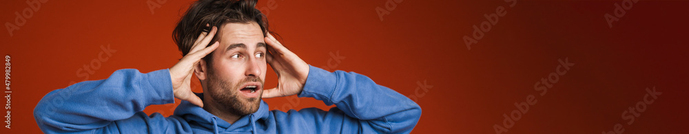 Young man holding his head while expressing surprise