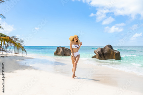 Beautiful woman enjoying the beautiful beachs of La Digue, Seychelles. Summer vacations on picture perfect tropical beach concept.