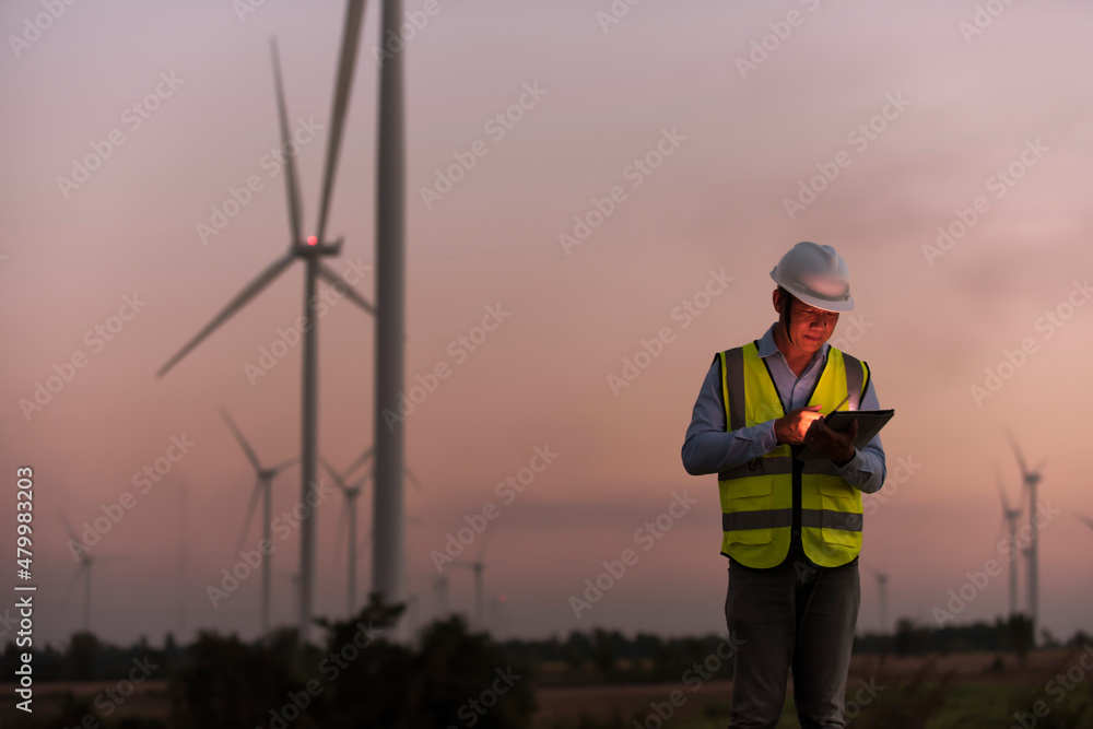 worker in the wind. Service engineers checking wind turbine on tablet on wind turbine farm Power Generator on background Station on mountain, Thailand people worker in the wind. Service engineers checking wind turbine on tablet on wind turbine farm Power Generator on background Station on mountain, Thailand people