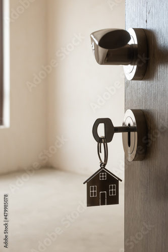 Open door to a new home. Door handle with key and home shaped keychain. Mortgage, investment, real estate, property and new home concept