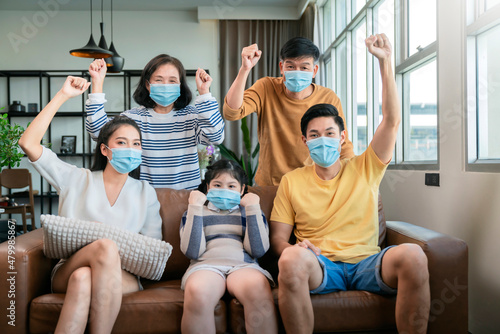 asian family strong together against covid virus epidemic spread,asian multi generation family with face mask cheering hand rise up show how strong healthy they have,family smile with confident home