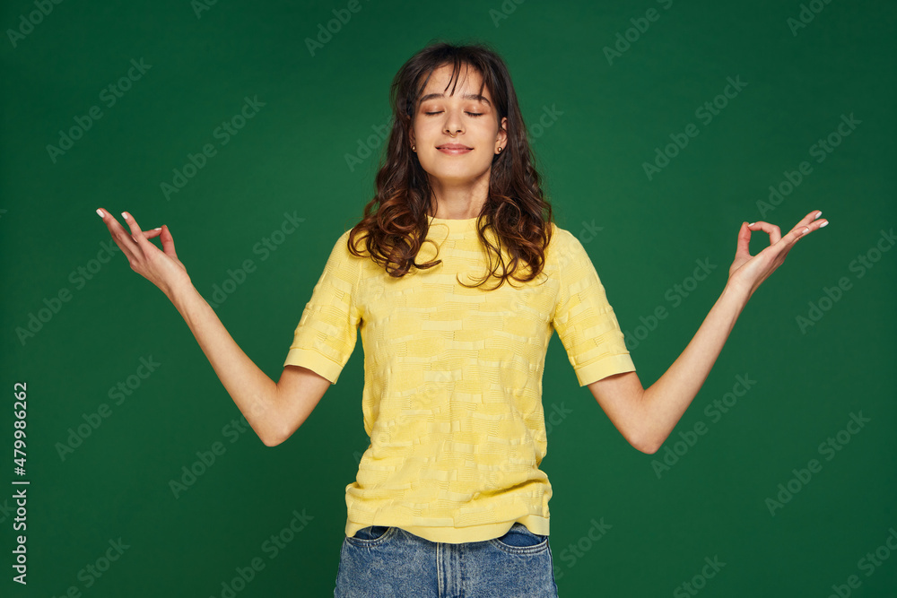 Calm young girl spreading hands in yoga om gesture folded fingers in mudra, closed eyes. No stress, healthy lifestyle Calm young girl spreading hands in yoga om gesture folded fingers in mudra, closed eyes. No stress, healthy lifestyle