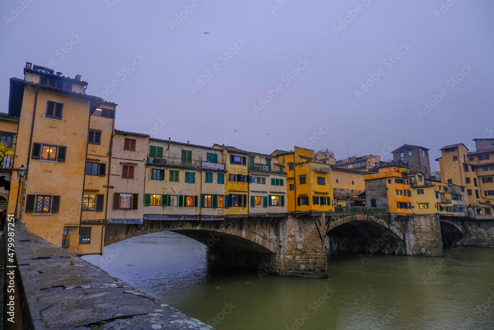 Florence, Italy: View on the Florence Ponte Vecchio with colorful stores on a rainy day across river Arno and dramatic gray sky