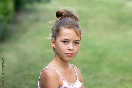 Outdoot portrait of a pretty girl in natural light isolated on green background. Annoyed teenager expression.