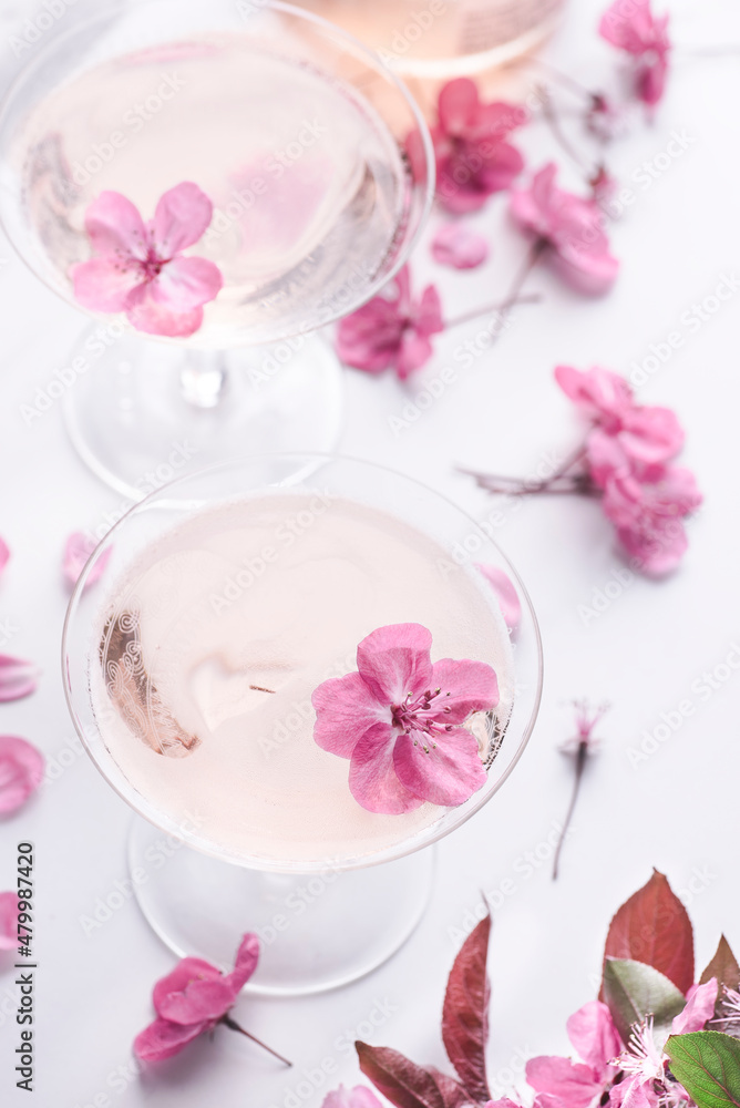 Romantic spingtime floral background with rose light sparkling wine in the two coupes  glasses with beautiful soft pink flowers, selective focus