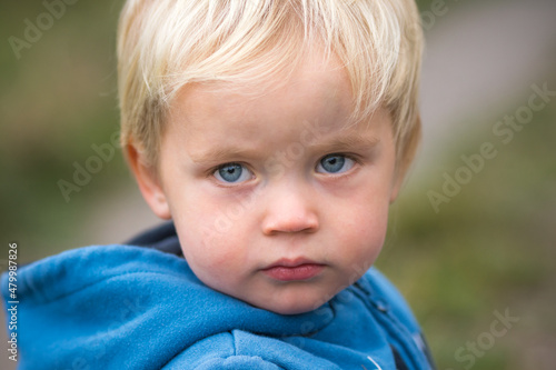Close up portrait of two years old caucasian kid. Blond child look angry and annoyed.