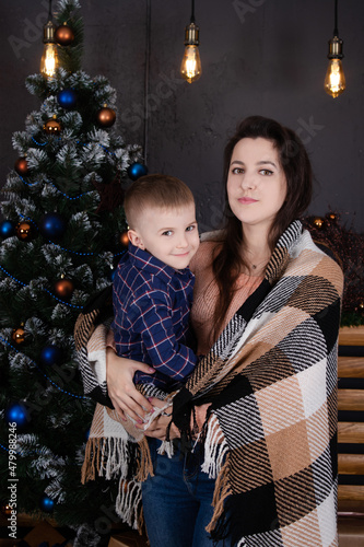 little toddler boy with woman near christmas tree and decoration. son and mother on christmas eve. new year. single mother. incomplete family.