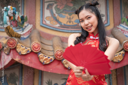 Beautiful portrait young Asian woman cheongsam dress smiling holding red envelope, girl celebrate with exciting, happy Chinese New Year, holiday concept.